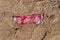 Plastic label of Coca-Cola on sandy beach after storm