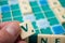 Plastic letters V in hand on Scrabble board game