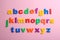 Plastic magnetic letters on pink background. Alphabetical order