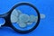 Plastic magnifier and a bunch of old silver coins on a blue table