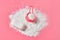 Plastic measuring spoon on heap of washing powder for cleaning clothes and antibacterial soap lies on pink countertop