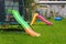 Plastic multi-colored slides on the playground. Green grass on the lawn