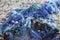 Plastic pollution - blue tangled fishing nets washed up on the b