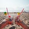 Plastic pollution in ocean environmental problem, hands holding plastic cups with straws and cocktail from beach garbage -