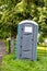 A plastic portable toilet next to a fence in a field at an outdoor event