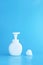 Plastic pump bottle and mousse foam or cleansing foam isolated on blue background, vertical with copy space. cleaning concept.