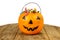 A plastic pumpkin filled with candy on wooden table