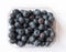 Plastic punnet full of lush blueberries against plain white background