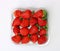 Plastic punnet full of lush strawberries against plain white background