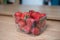 Plastic punnet of strawberries on a wooden table