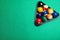 Plastic rack with billiard balls on green table, top view. Space for text