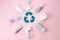 Plastic recycling sign. Used cosmetic tubes and beauty products on pink background. Save the planet. flat lay. top view