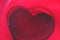 A plastic red heart at the bottom of a red wine glass