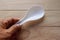 Plastic rice spoon white in hand  on wooden background closeup. Kitchenware to necessary