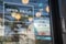 A plastic sign in front of mirror at the entrance of coffee shop. Text open on at the automatic door. There are information of