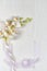 A plastic sprig of orchid with silk ribbon lay flat still life