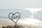 Plastic stick in shape of heart and word Love in sand on beach seashore