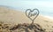 Plastic stick in shape of heart and word Love in sand on beach seashore