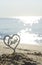 Plastic stick in shape of heart and word Love in sand on beach seashore