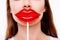 Plastic surgery concept. Cropped close up photo of young woman holding big red lips shaped candy near the mouth on white backgroun