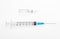 Plastic syringe with open needle and transparent white glass ampoule with a drug