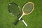 Plastic tennis and wooden badminton rackets on green lawn