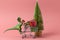 plastic toy dinosaur driving shopping trolley full of present boxes against evergreen tree on a pink background ,shopping