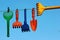 Plastic toy rakes and shovels on a clothing line against blue sky background