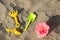 Plastic toy shovels and bucket on beach sand in summer day