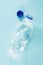 Plastic waste concept: discarded crumpled water bottle in blue background, detailed view