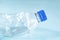 Plastic waste concept: discarded crumpled water bottle in blue background, detailed view