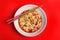 Plate of asian noodles with broth, vegetables and chopsticks on color background