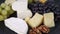 A plate of assorted mouldy goat's milk cheeses on a wooden Board with green grapes