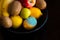A plate with assorted whole multi-colored ripe fruits, including moldy lemon. Kiwi, apples, bananas, lemons