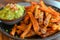 Plate of baked sweet potato fries with a side of guacamole