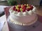 Plate with beautiful whipped cream cake with strawberries and grapes on top