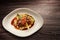 Plate of beef on vegetables and gravy on wooden background