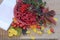 Plate with berries of barberry on the old boards next to the tissue paper and autumn leaves and scattered berries rose hips