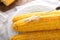 Plate with boiled corncobs and butter on table, closeup