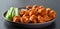 Plate of boneless chicken wings with buffalo sauce and celery sticks