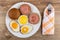 Plate with bread, bowl of mayonnaise, fried eggs, sandwiches with sausages, fork on table. Top view