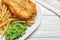 Plate with British traditional fish and potato chips on wooden background