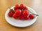 Plate with a bunch of mini tomatoes on wooden table.