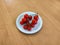 Plate with a bunch of mini tomatoes on wooden table.