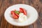 Plate of capreze salad - fresh tomatos and a piece of mozzarella cheese on wooden table