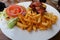 A plate of cheese burger with bacon, tomatos, onions and french fries