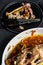 A plate of chicken bones and a chicken skeleton in a baking dish. Leftovers from dinner. Black background. Top view