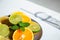 Plate of citrus fresh fruit on a white table, next to the shadow of the glass