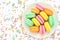 Plate of colorful macarons on bright festive decor background, sweet confection