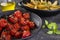 Plate of confit tomatoes  and roasted potatoes with rosemary in iron casserole on dark background